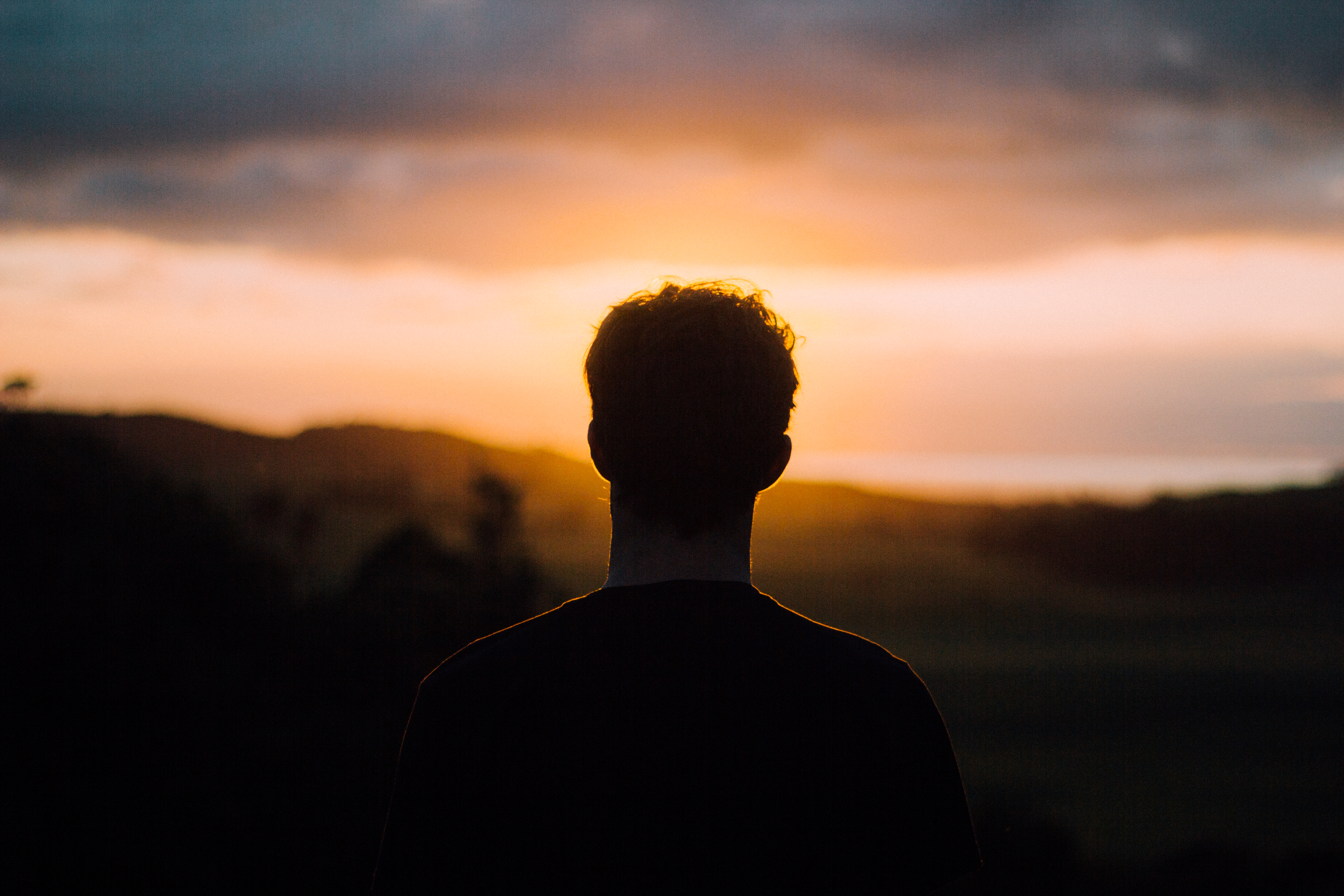 Man_watching_Muriwai_sunset_(Unsplash)